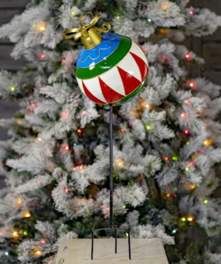 31 inch tall multi-colored metal Christmas ball ornament yard stake with metallic gold ribbon bow on top in front of light-up tree