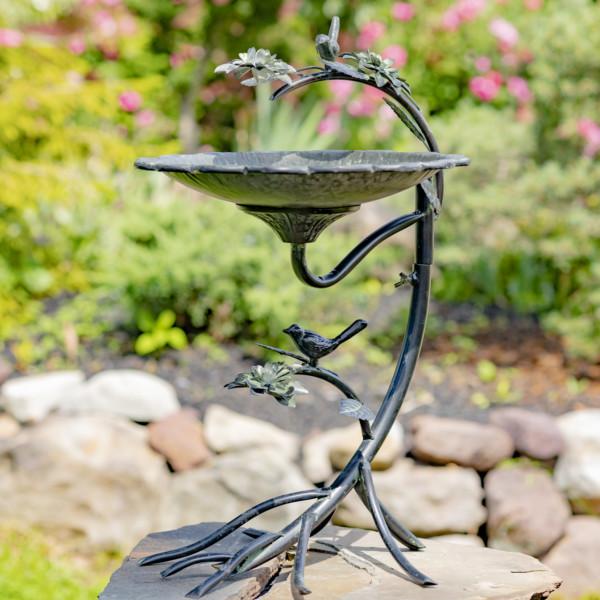 Scallop edge birdbath in a galvanized finish with legs shaped like a branch with vines coming out and two birds perched on each vine