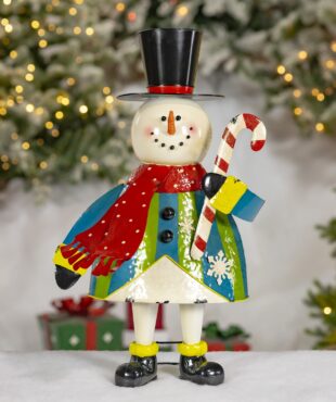 This is a cute snowman figurine with a smiling face, a carrot nose, and black button eyes and mouth. It wears a tall black top hat, a red scarf, and a colorful coat with blue, green, and white patterns, including snowflakes. The snowman is holding a red and white striped candy cane and has black boots on its feet.