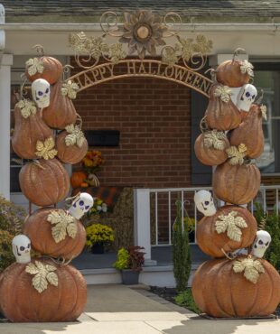 9.6 feet tall large iron Halloween arch with orange pumpkins, white skulls with purple LED lights, golden leaves and Happy Halloween sign in front of house entrance