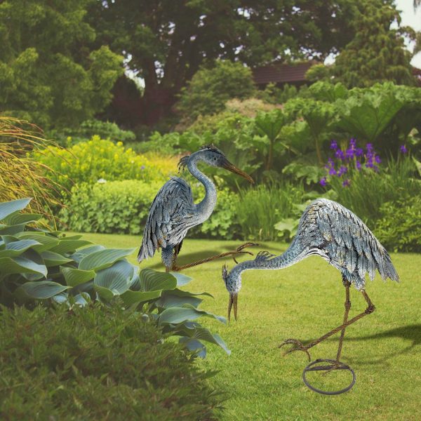 Two heron figurines displayed in a yard with a detailed hand painted design in colors blue-grey