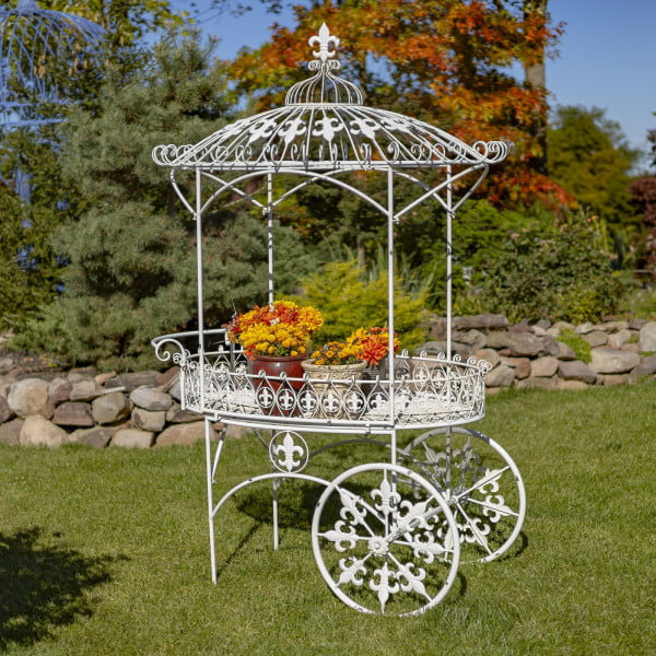 iron flower cart with two wheels and canopy roof decorated with fleur-de-lis details and flower pots standing on it hand-painted in antique white distressed finish