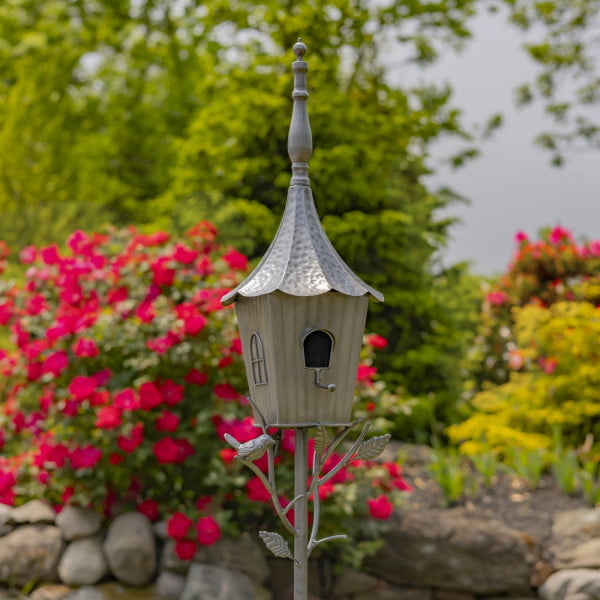 closed up image of iron cone roof birdhouse stake in antique silver hand-painted finish with little bird perched on decorative leaf