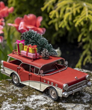 Red and Cream Colored Metal Station Wagon with Christmas Gifts and Tree Strapped to the top of the Roof