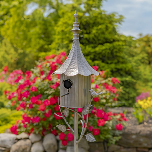 closed up image of iron cone roof birdhouse stake in antique silver hand-painted finish with little bird perched on decorative leaf