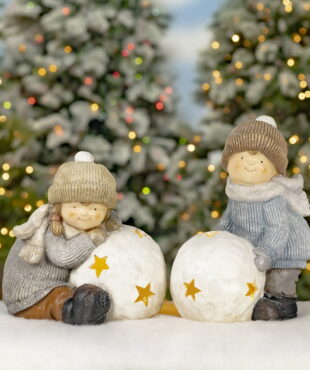 boy and girl figurines in winter clothes playing snowballs lanterns with star cutouts