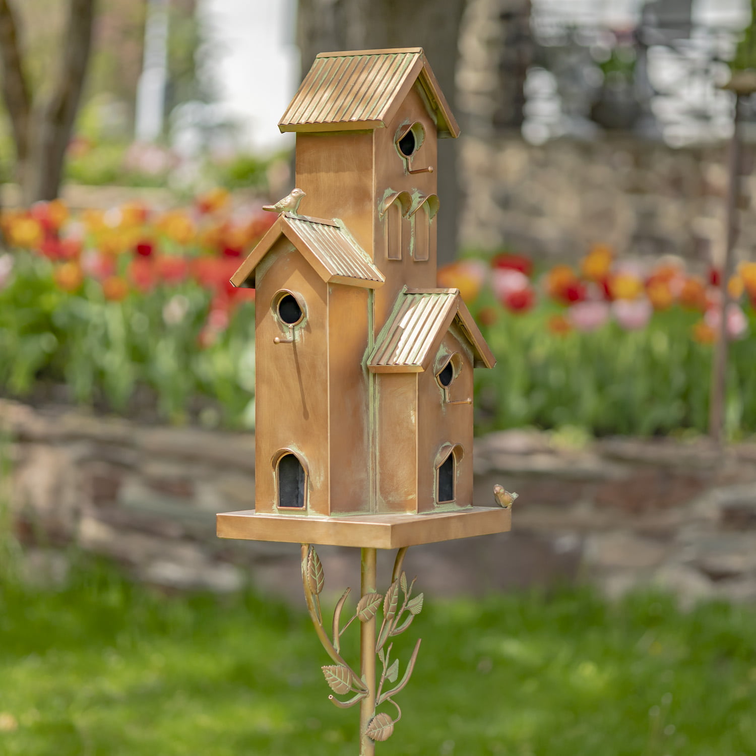 Metal multi-family birdhouse stake in a classic style with short chimney and little bird perched on top of it painted in antique copper finish with patina accents
