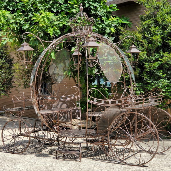 Large iron round pumpkin-like Cinderella carriage with 4 hanging lanterns and multiple planters equipped with 2 entrances, 2 benches, and steps for easy access a real rotating wheels in antique bronze finish
