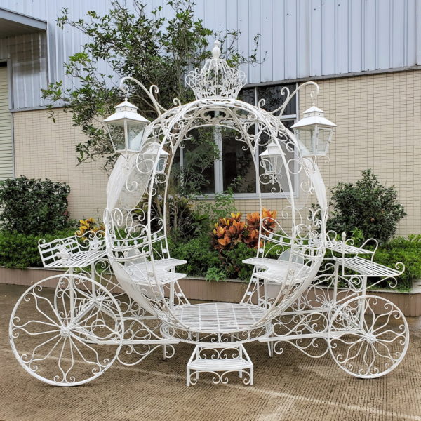 Large iron round pumpkin-like Cinderella carriage with 4 hanging lanterns and multiple planters equipped with 2 entrances, 2 benches, and steps for easy access a real rotating wheels in antique white finish