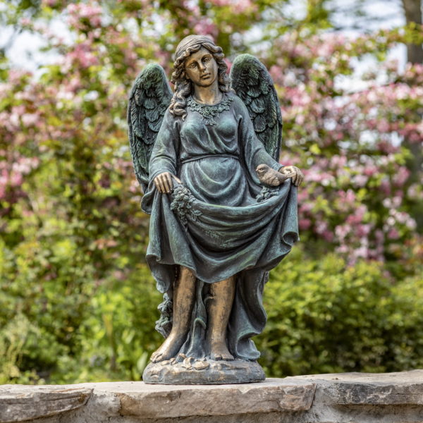 Antique bronze tall angel magnesium statue holding up her dress creating a birdbath while a bird is perched at the edge of her dress and she is admiring it with two wings folded behind her