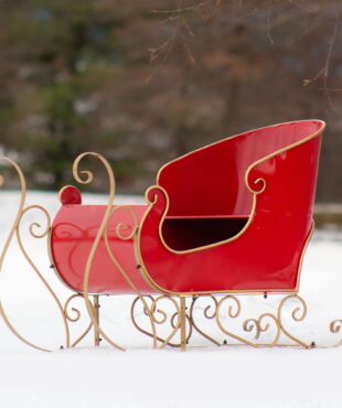 Metal holiday sleigh decoration in red with gold rails
