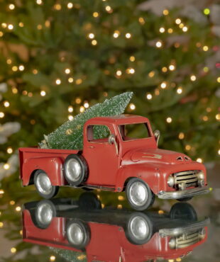 16 inches long classic red vintage iron pick up with Christmas tree in trunk on a tabletop