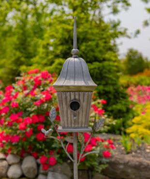 front view of iron cone roof birdhouse stake in antique silver hand-painted finish with little bird perched on decorative leaf