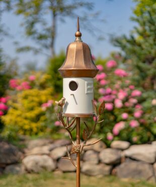 image of Iron and White porcelain birdhouse stake with bell roof and a little bird perched on leaves attached to the stake