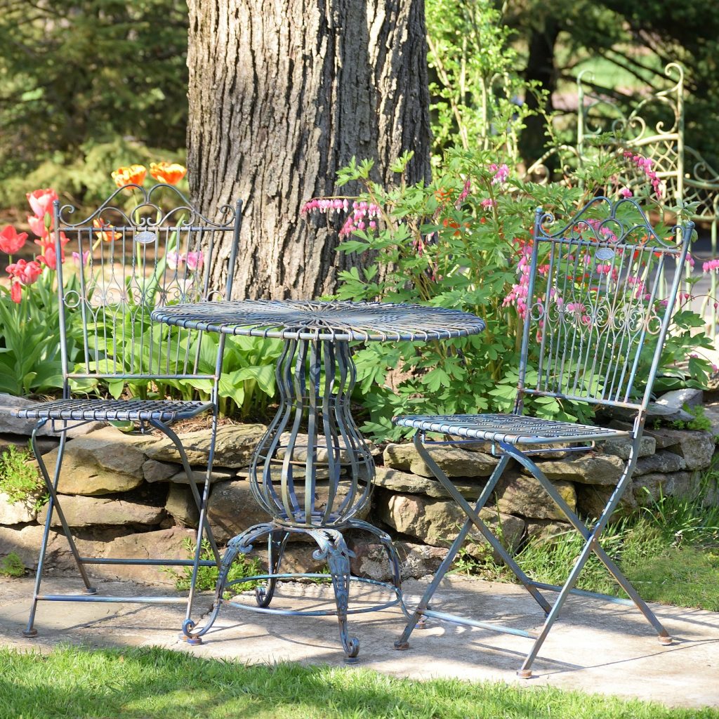 three piece iron bistro set with distressed antique blue finish includes two folding metal chairs and one round table with pretty decorative stand