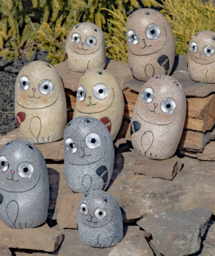 One set of nine Solar Rock Cats sitting on some rocks in Cream Grey and Peru looking at you with there large round eyes that lights up in the dark