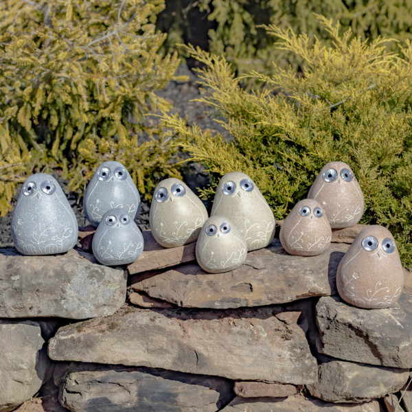 Nine Solar Rock Birds in three sets of colors antique beige, antique grey and peru with floral etching sitting on some rocks watching you with there round eyes that lights up