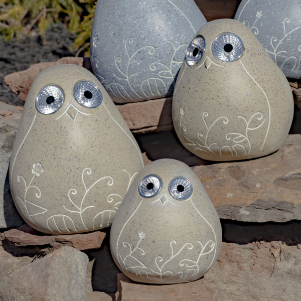 One set of three beige solar bird rocks with floral etching sitting on some rocks looking at you with there round big eyes that lights up in the dark
