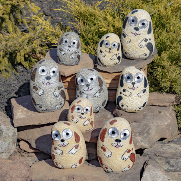 One set of nine solar rock dogs in Antique Grey, Ivory and Peach sitting on a rock with eyes that light up in the dark