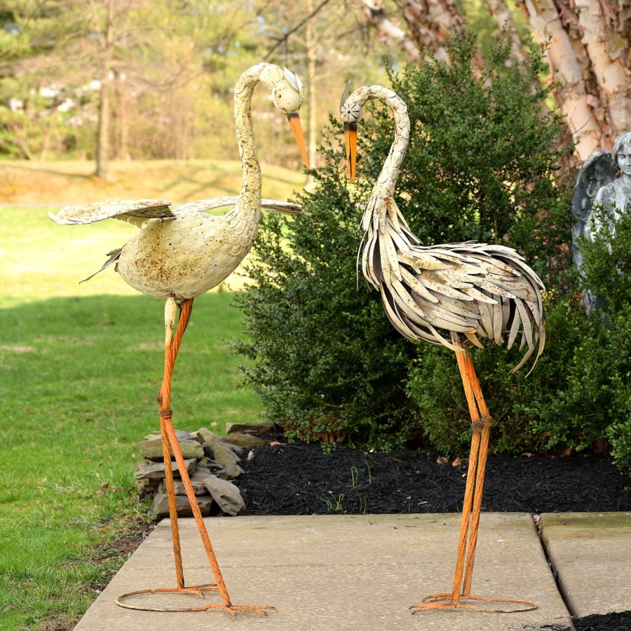 Two large white Herons standing tall looking down with there tall orange feet