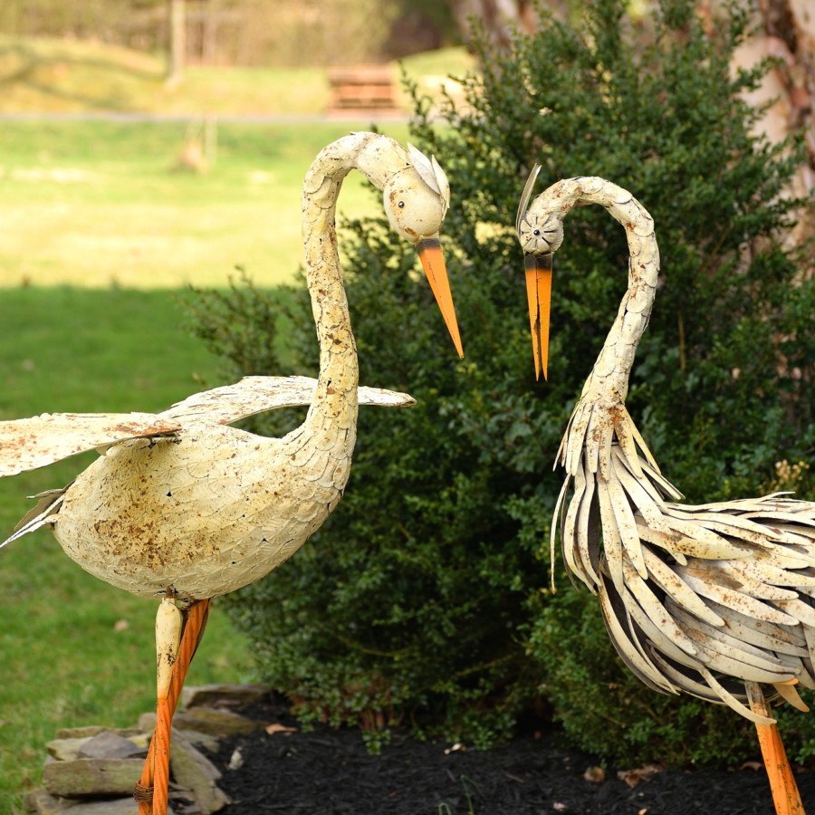 Close up image of Two large white Herons standing tall looking down with there tall orange feet