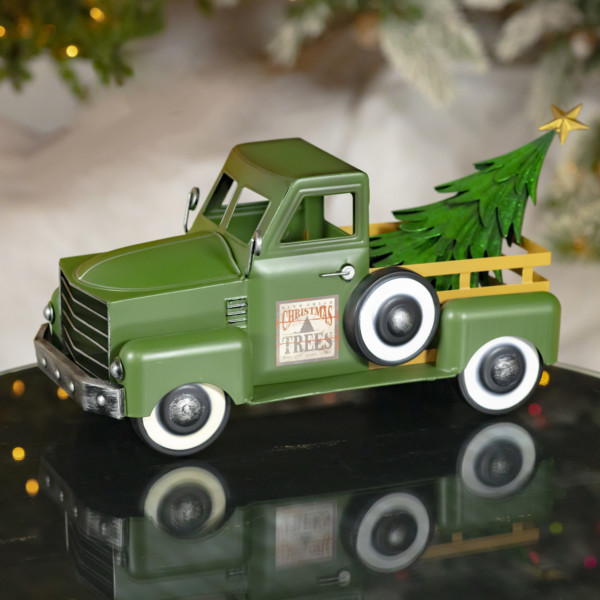 Small green iron truck with yellow bars to the back of the truck with christmas tree in the tray