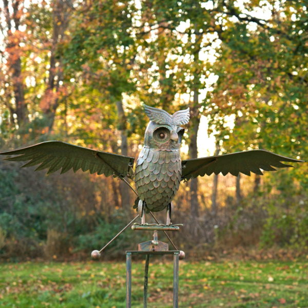 top half of 81 inch tall large metal rocking owl garden stake with flapping wings in distressed bronze finish with Autumn landscape background