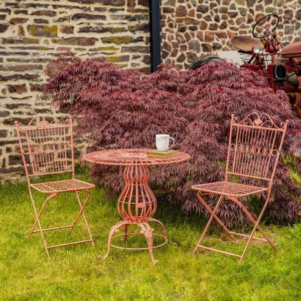 three piece iron bistro set with distressed flamingo pink finish includes two folding metal chairs and one round table with pretty decorative stand