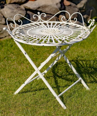 Victorian-style wrought iron folding garden table with X-shaped legs and filigree details in antique white distressed finish in garden