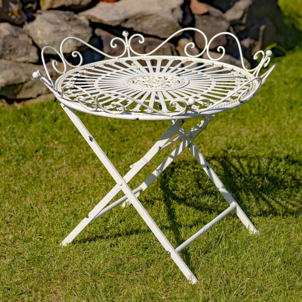 Victorian-style wrought iron folding garden table with X-shaped legs and filigree details in antique white distressed finish in garden