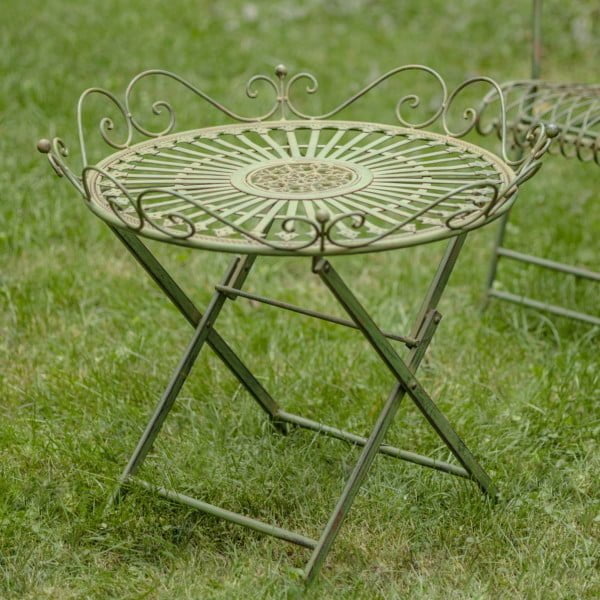 Victorian-style wrought iron folding garden table with X-shaped legs and filigree details in antique green distressed finish in garden