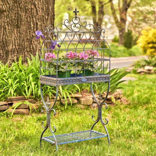 rectangular metal bird cage plant stand with fleur-de-lis details and shelf in antique blue distressed finish with flower pots inside it