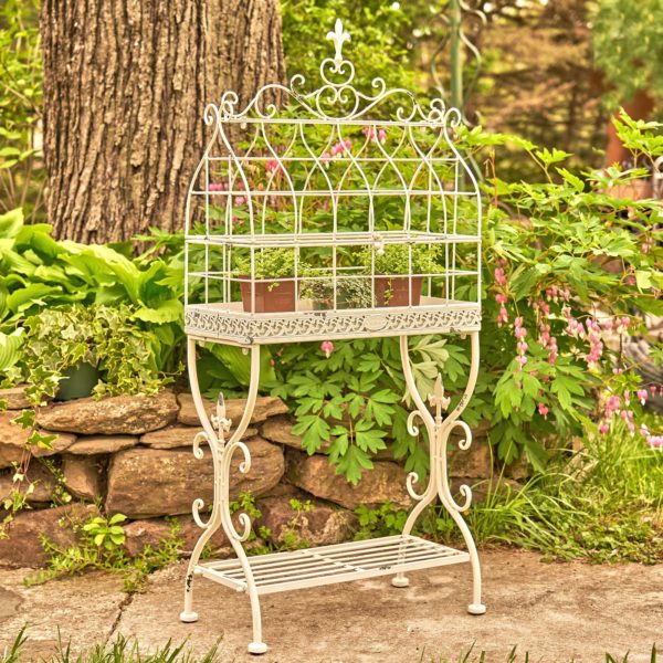 rectangular metal bird cage plant stand with fleur-de-lis details and shelf in antique white distressed finish with two flower pots inside it