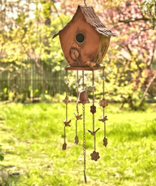 full length image of metal hanging on a chain birdhouse with curved roof and wind chimes in antique copper finish