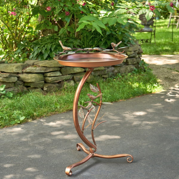 Iron shallow birdbath with branch stand on birds on the basin edge in copper finish standing in garden