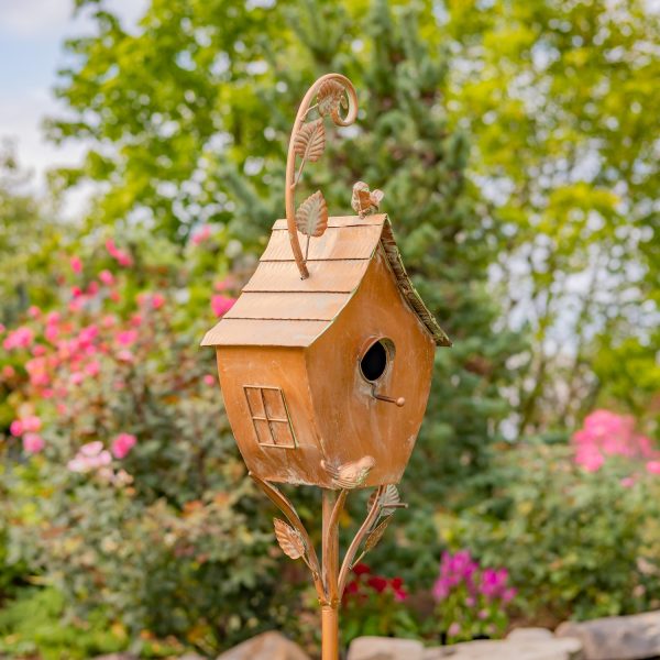 metal birdhouse with curved roof and a little bird perched on it painted in antique copper finish with patina details