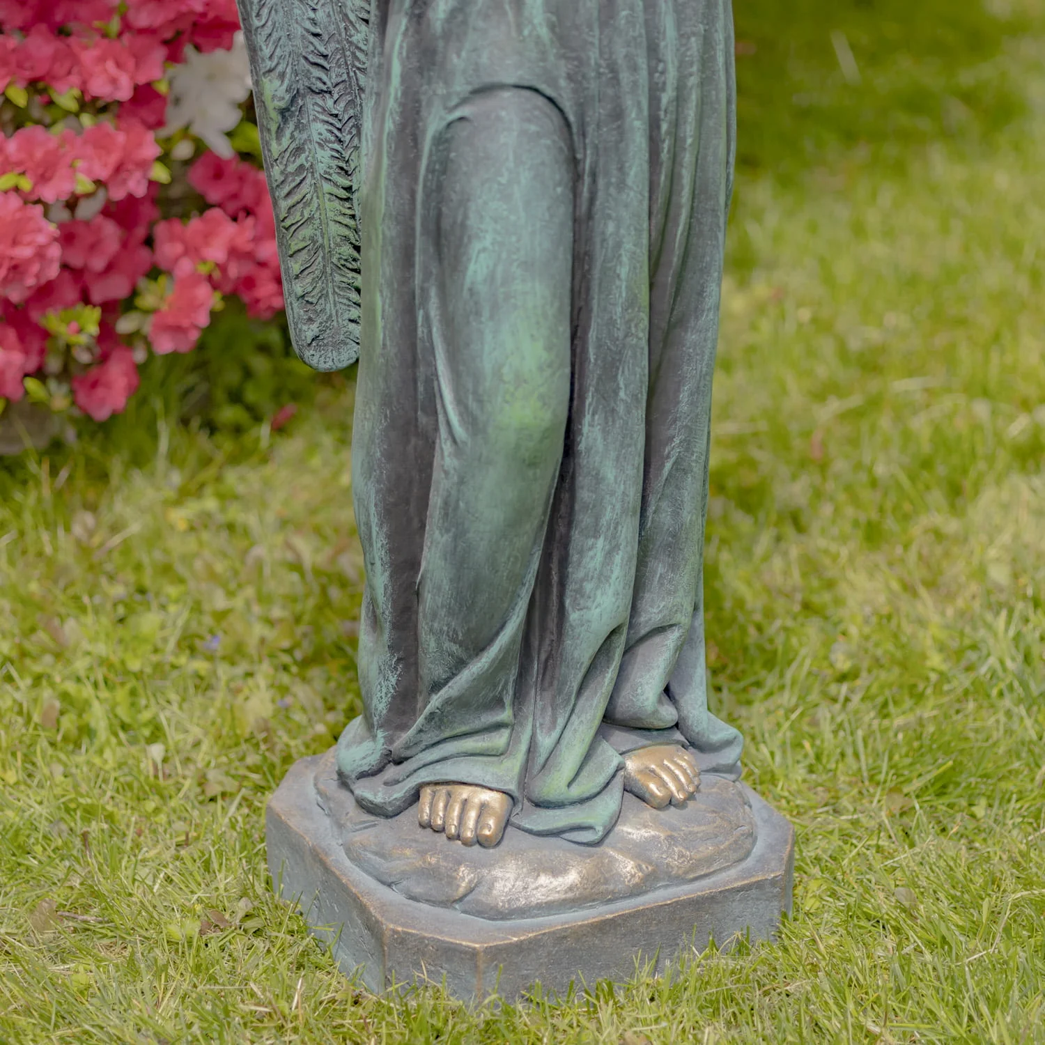 closed up image angel's legs standing on a stone pedestal in antique bronze painted finish