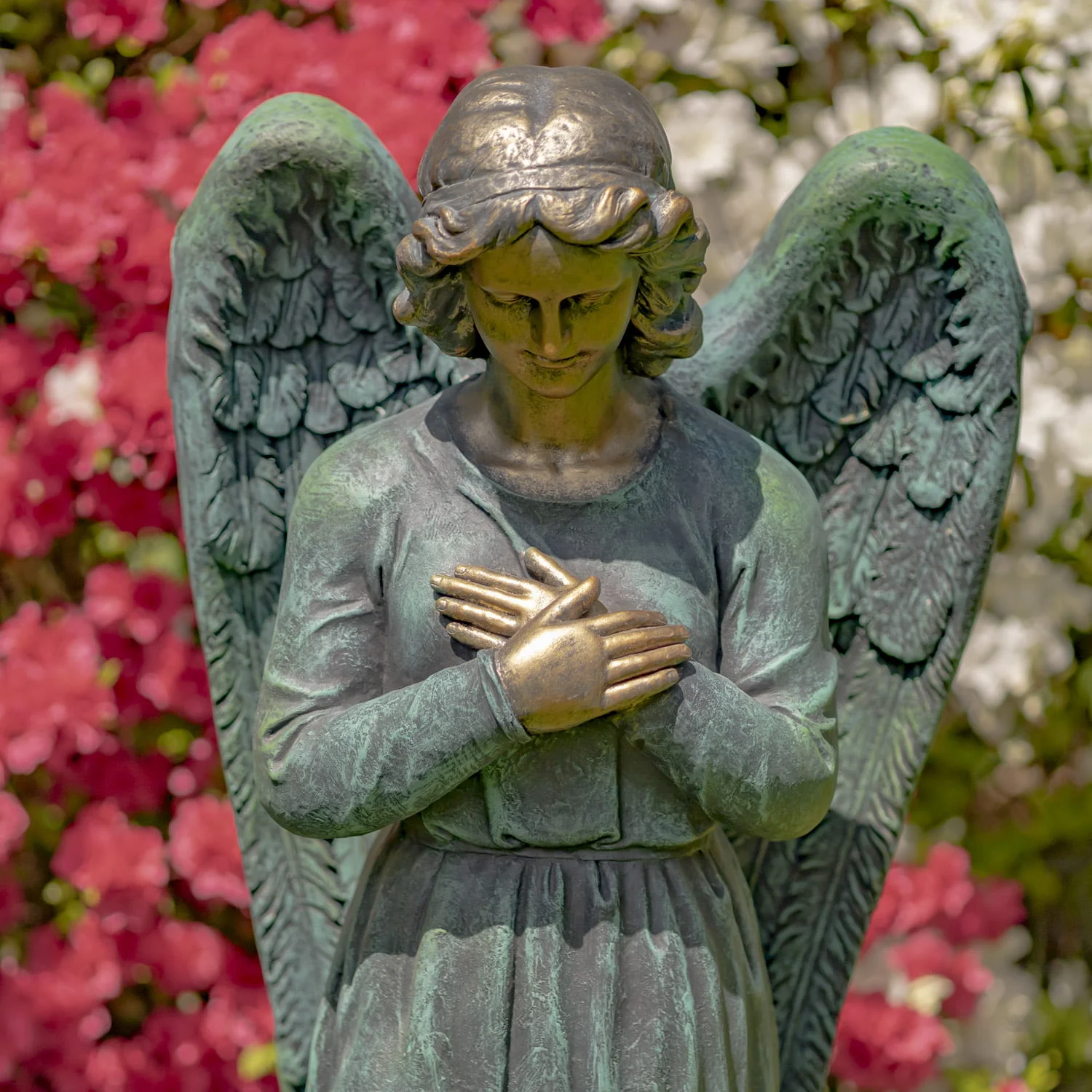 closed up image of angel statue holding heart in distressed antique bronze finish in garden