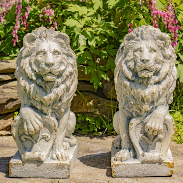 Two magnesium Lion statue in antique grey sitting upright one paw cocked on a shield