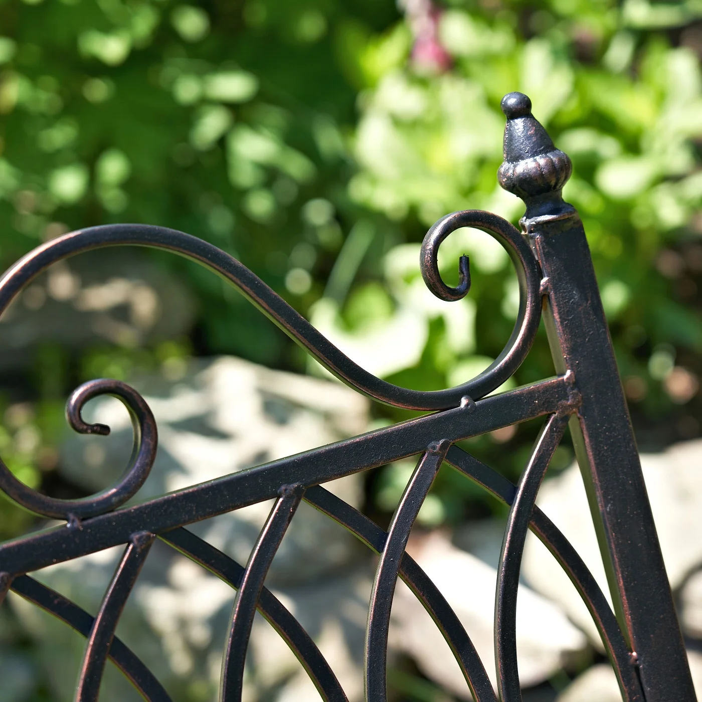 close up backrest with filigree details and finial in antique bronze finish