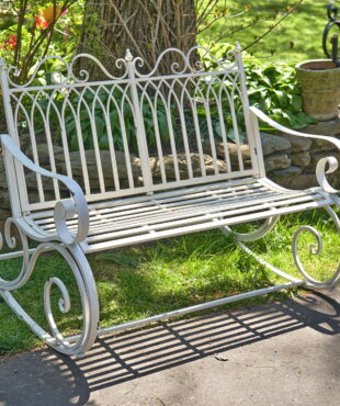 Iron rocking bench with filigree armrest and bottom part in antique white finish in garden
