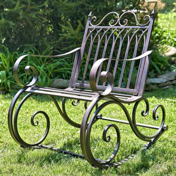 side view of Iron rocking chair with with filigree armrest and bottom part in antique bronze finish in garden