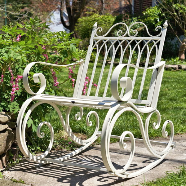 Iron rocking chair with with filigree armrest and bottom part in antique white finish in garden