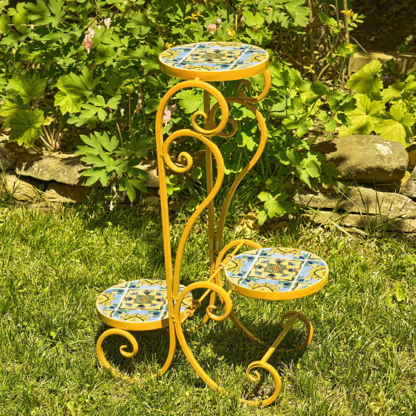 Three tier iron yellow plant stand with mosaic tiles in garden