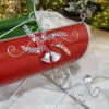 close up front part of large Victorian Christmas sleigh in red, green and silver with silver bells. bow and sprigs