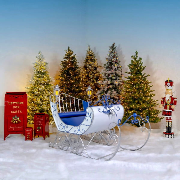 Large Victorian Style Christmas Sleigh Kutaisi in Blue, White, and Silver standing next to nutcracker and 3 mailboxes