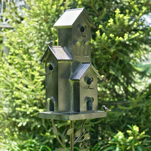 side view of Galvanized metal multi-family birdhouse stake in a classic style with short chimney and little bird perched on top of it with patina accents
