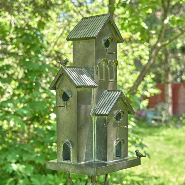 Galvanized metal multi-family birdhouse stake in a classic style with short chimney and little bird perched on top of it with patina accents