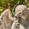 Close up image of the antique grey angel statue head slightly tilt facing down with her wavy hair flowing down her neck