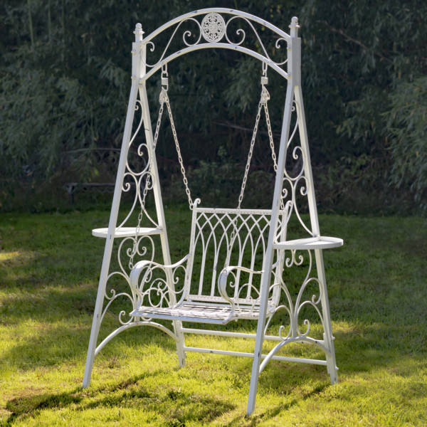 Antique white iron swing chair with curlicue designs on the sides